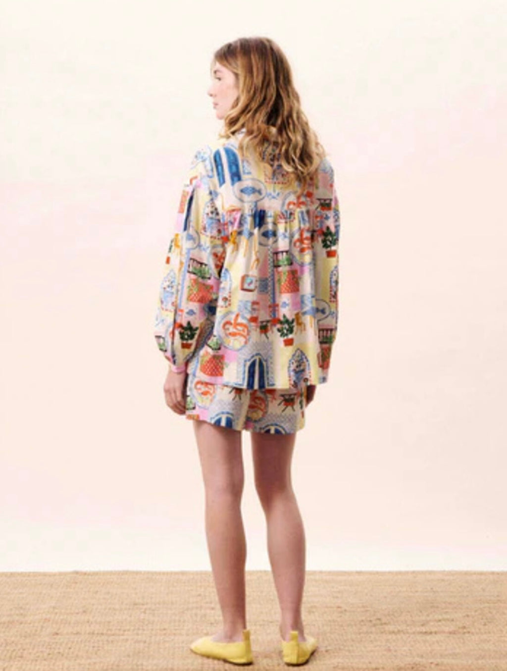 Woman wearing a colorful patterned dress against a plain background