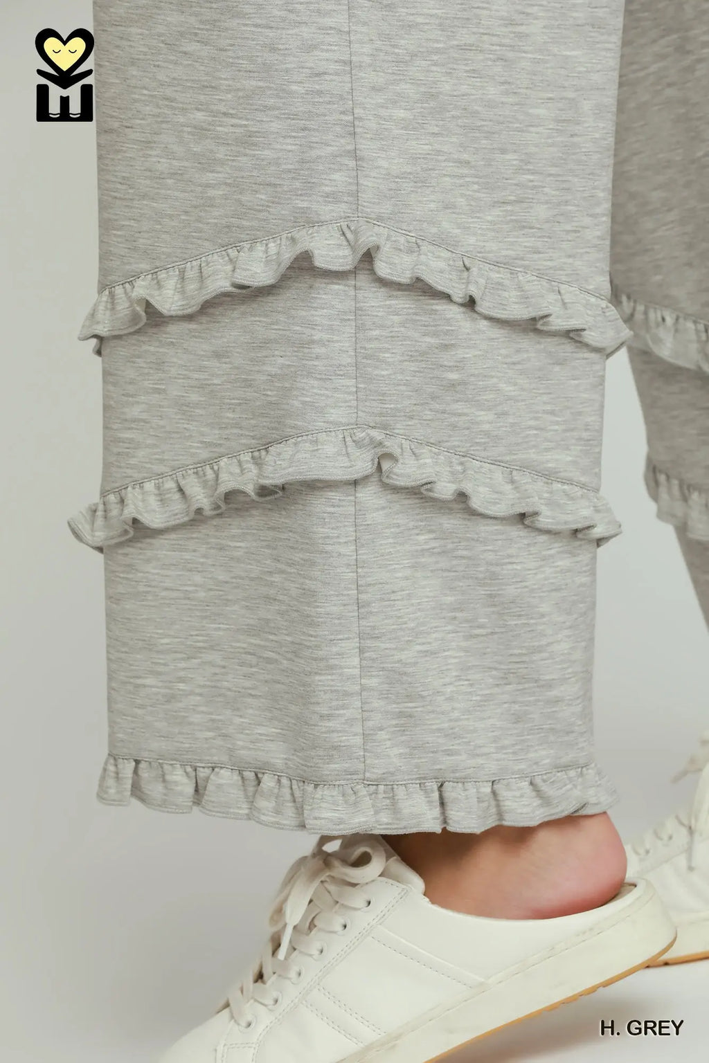 Gray ruffled skirt worn with white sneakers on a light gray background