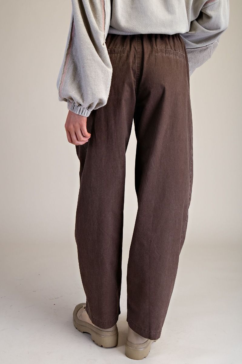 Person wearing brown pants and a light gray sweatshirt on a plain background
