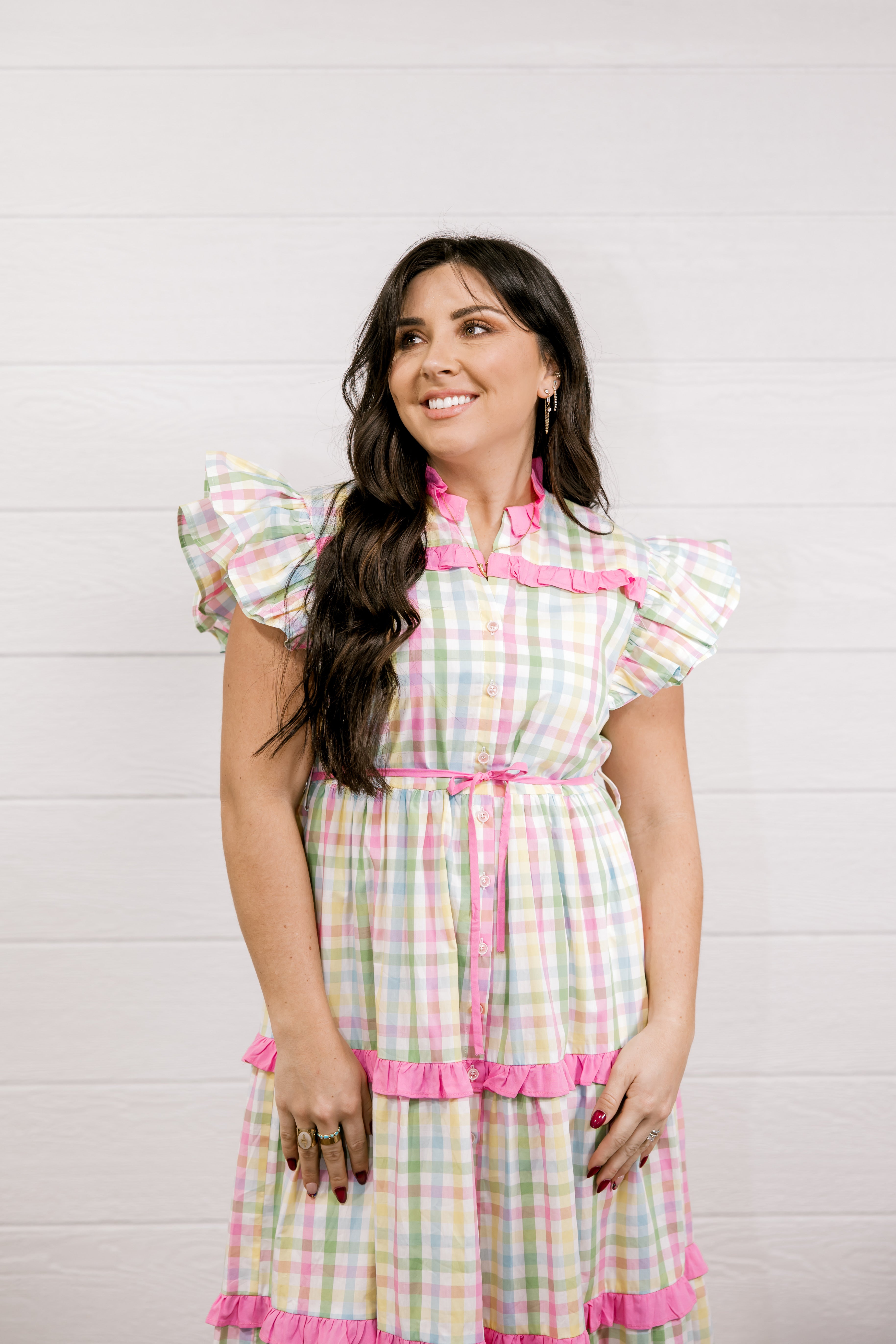 Woman wearing a colorful checkered dress with pink accents against a white background