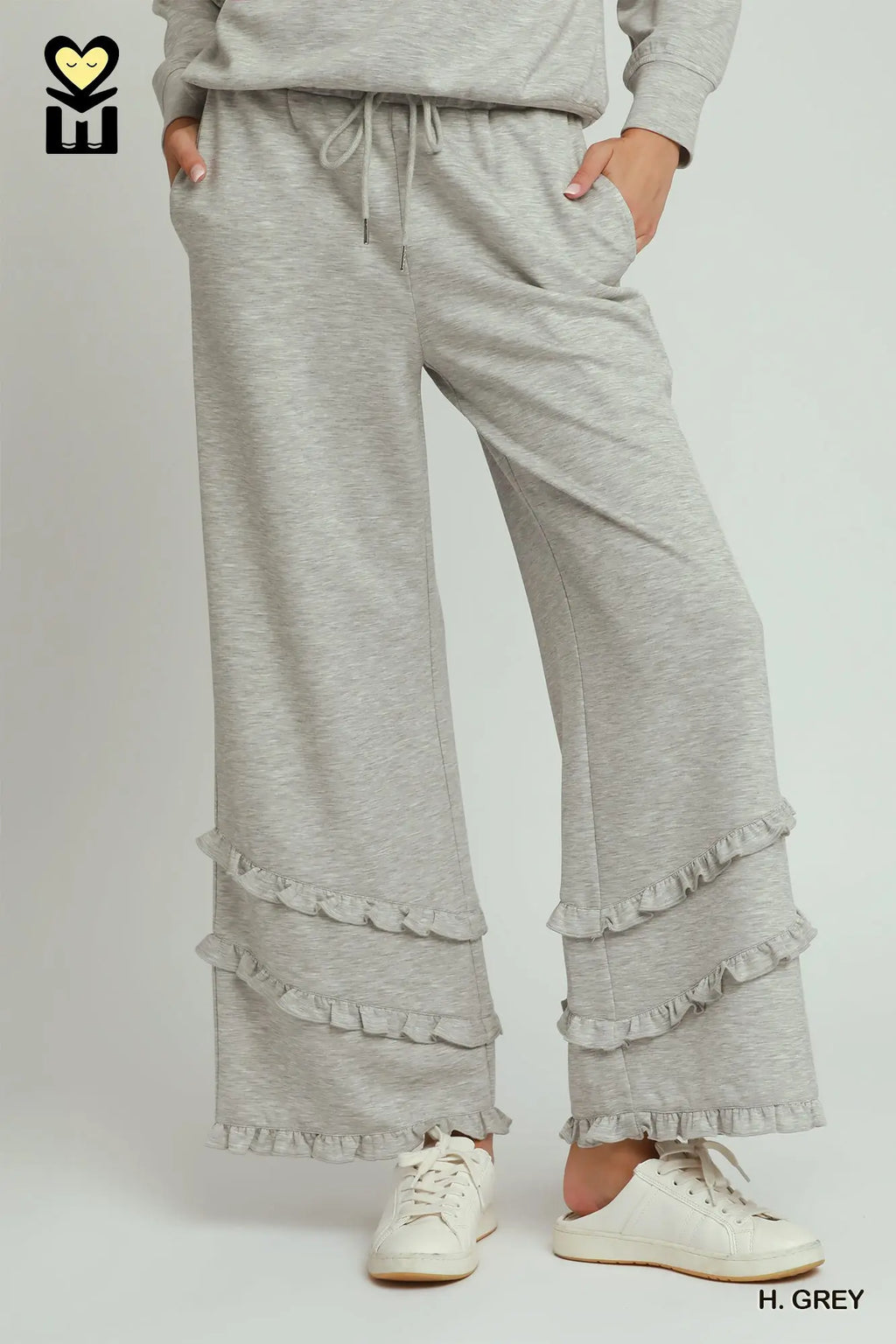 Gray ruffled pants worn by a person on a white background