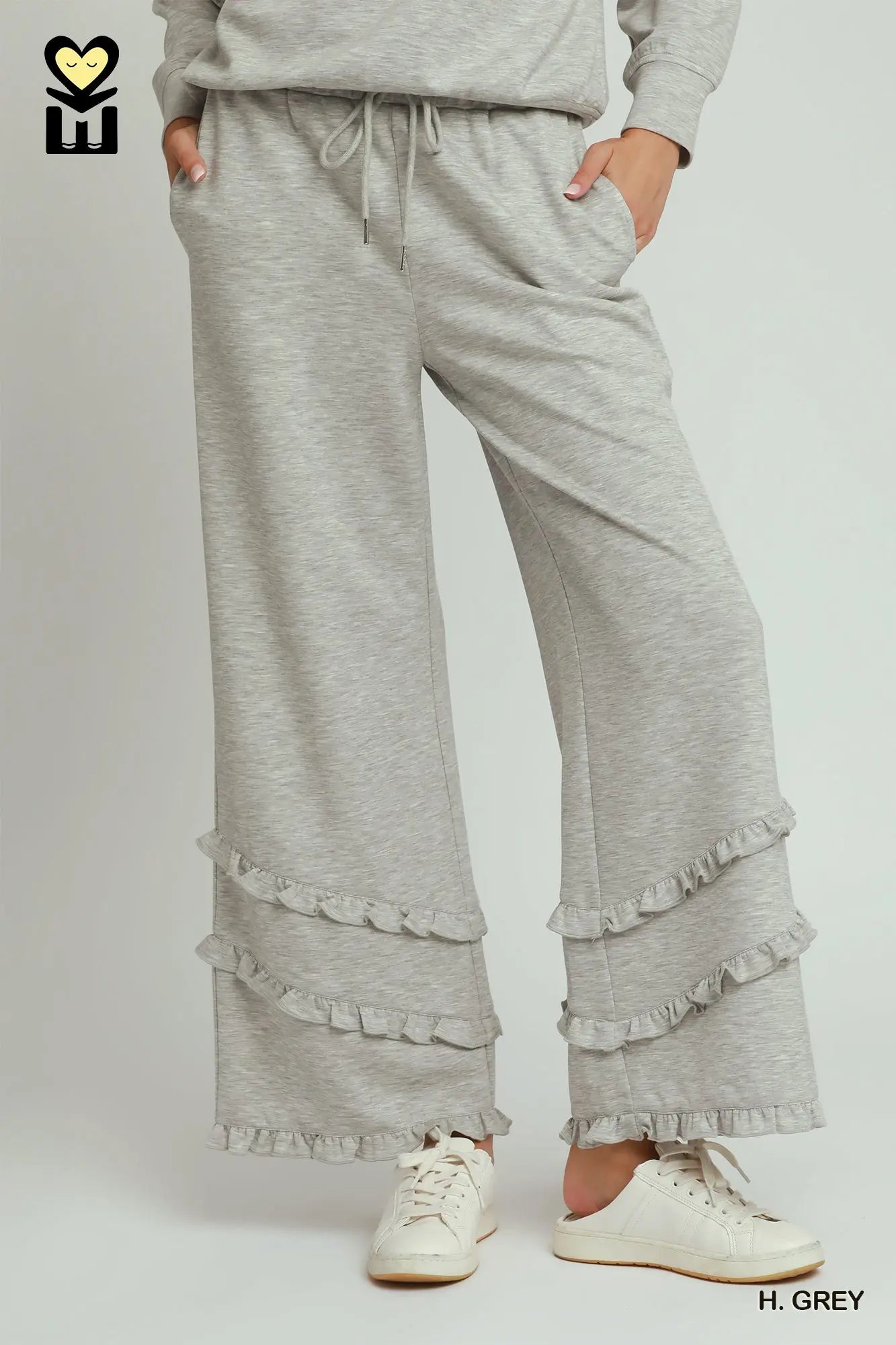 Gray ruffled pants worn by a person on a white background
