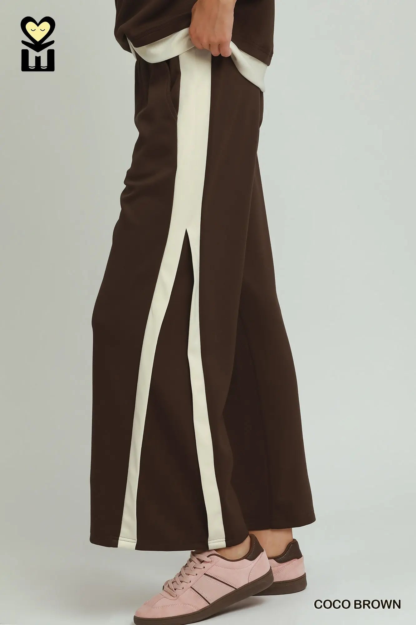 Brown pants with white stripes worn by a person on a plain background