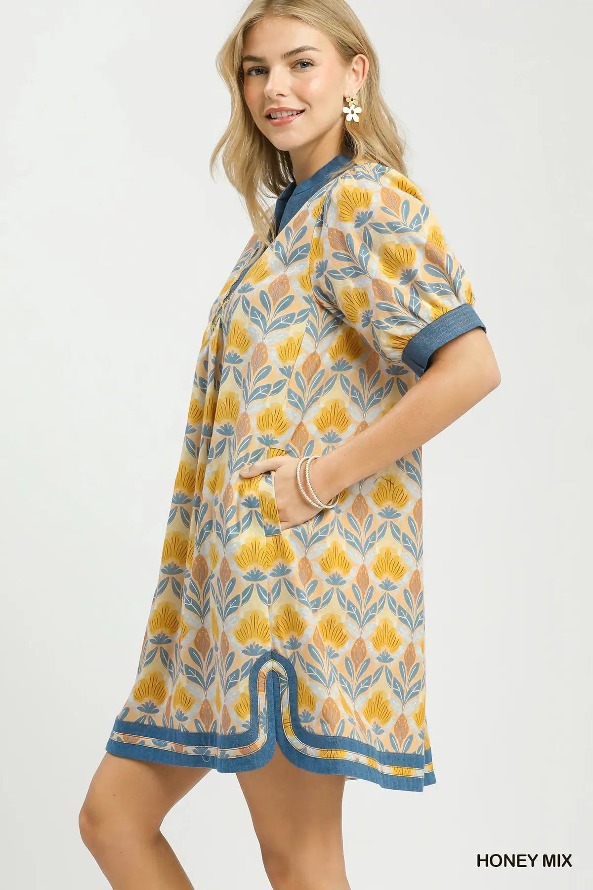 Woman wearing a patterned dress with a honey mix color scheme on a white background