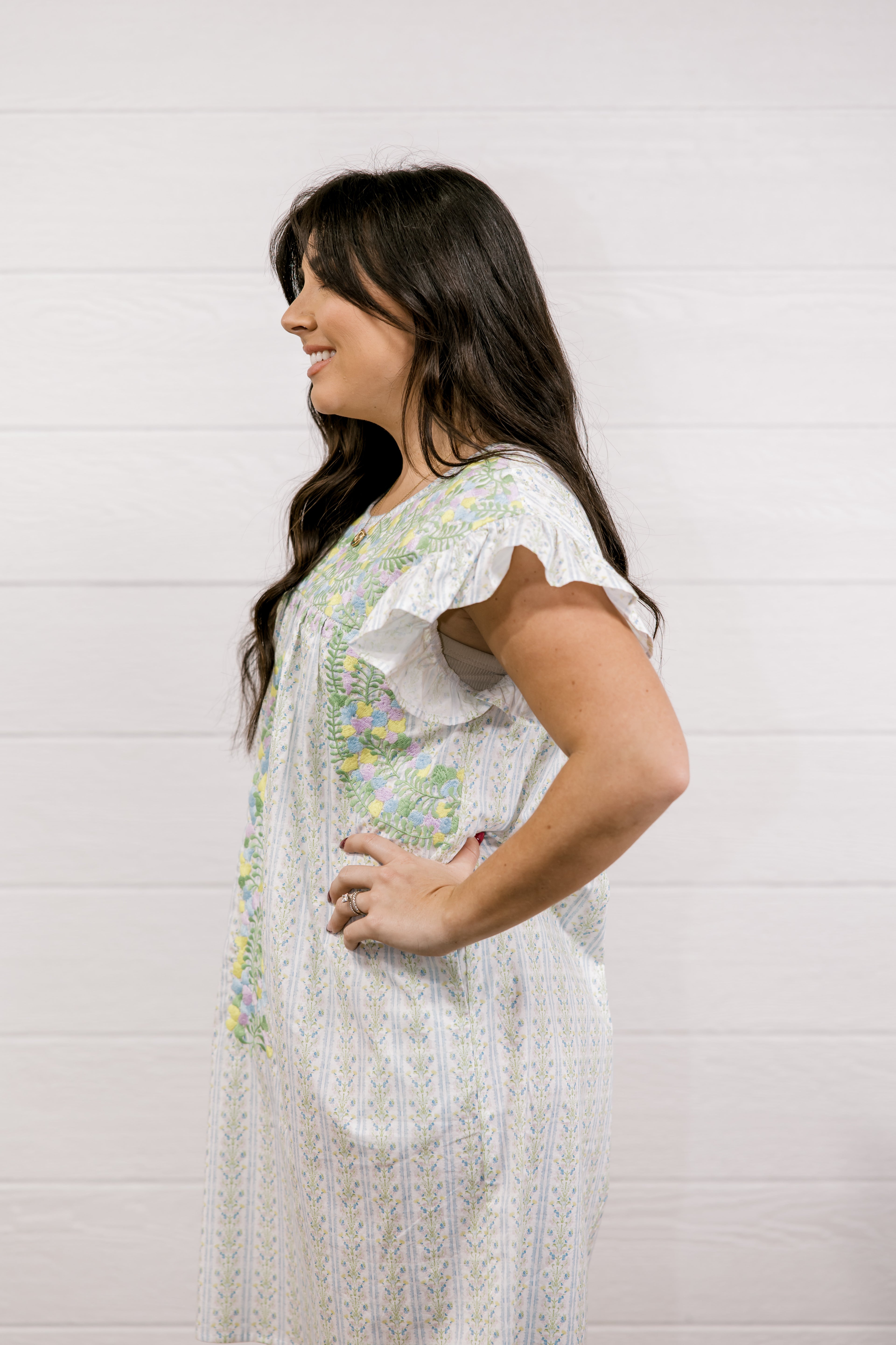 Woman wearing a white floral dress against a light background