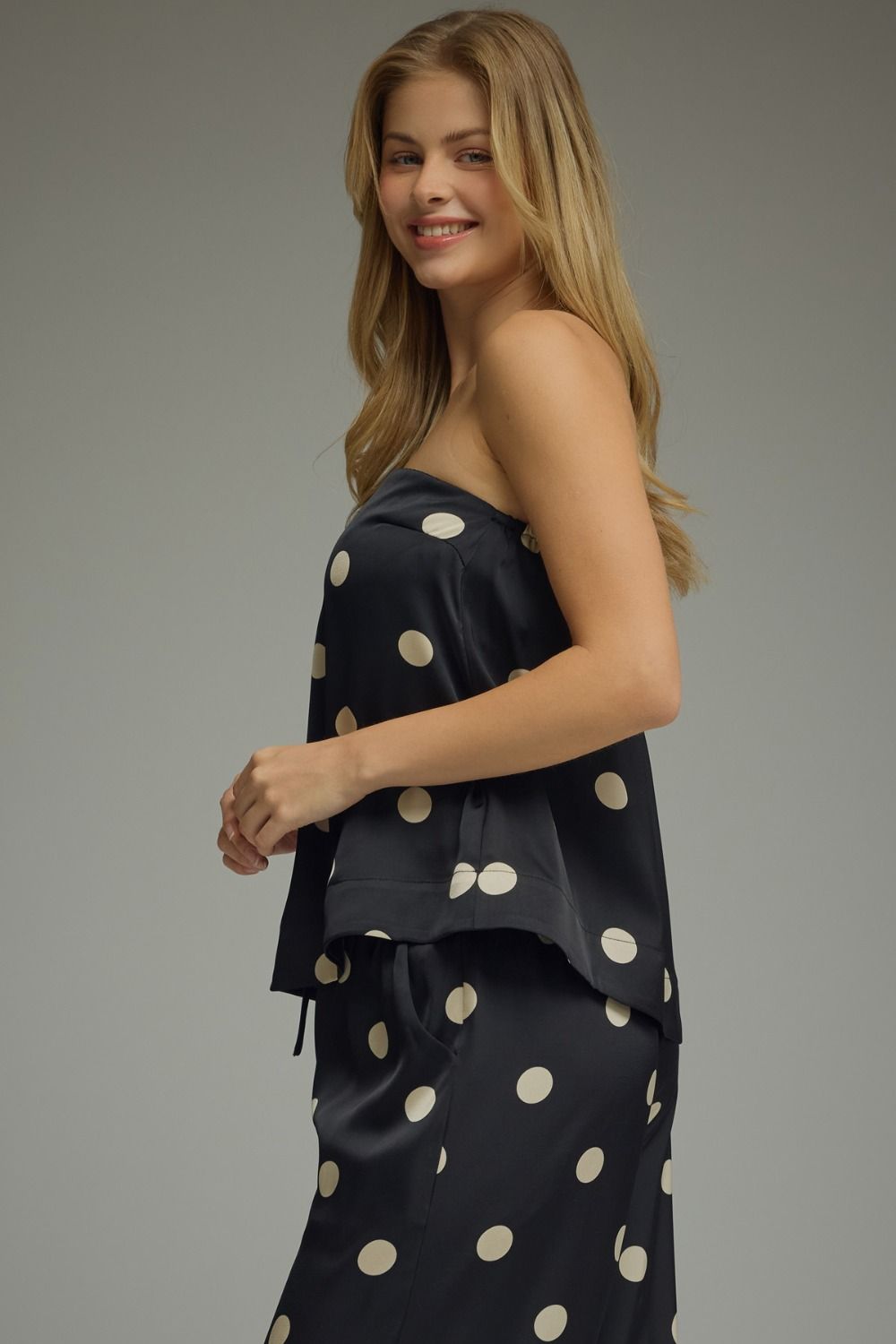 Woman wearing a black dress with white polka dots on a gray background