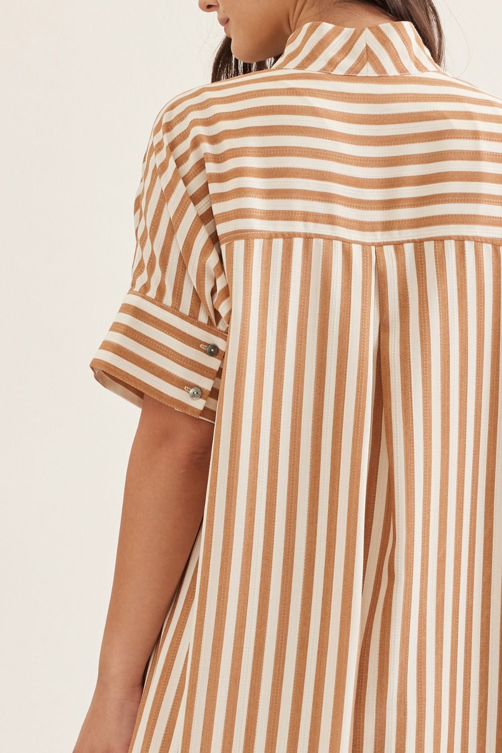 Brown and white striped shirt worn by a person on a plain background