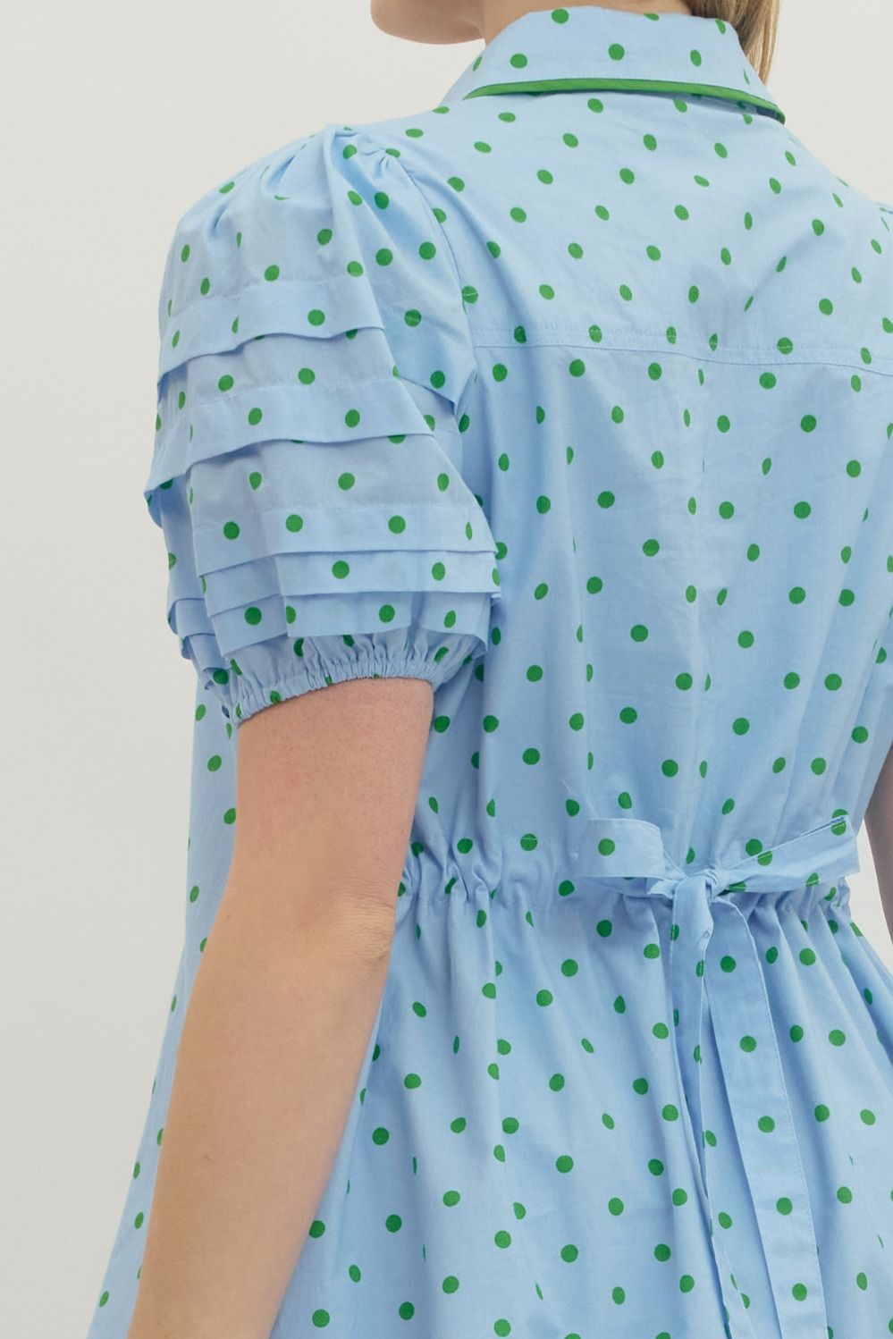 Light blue dress with green polka dots on a plain background