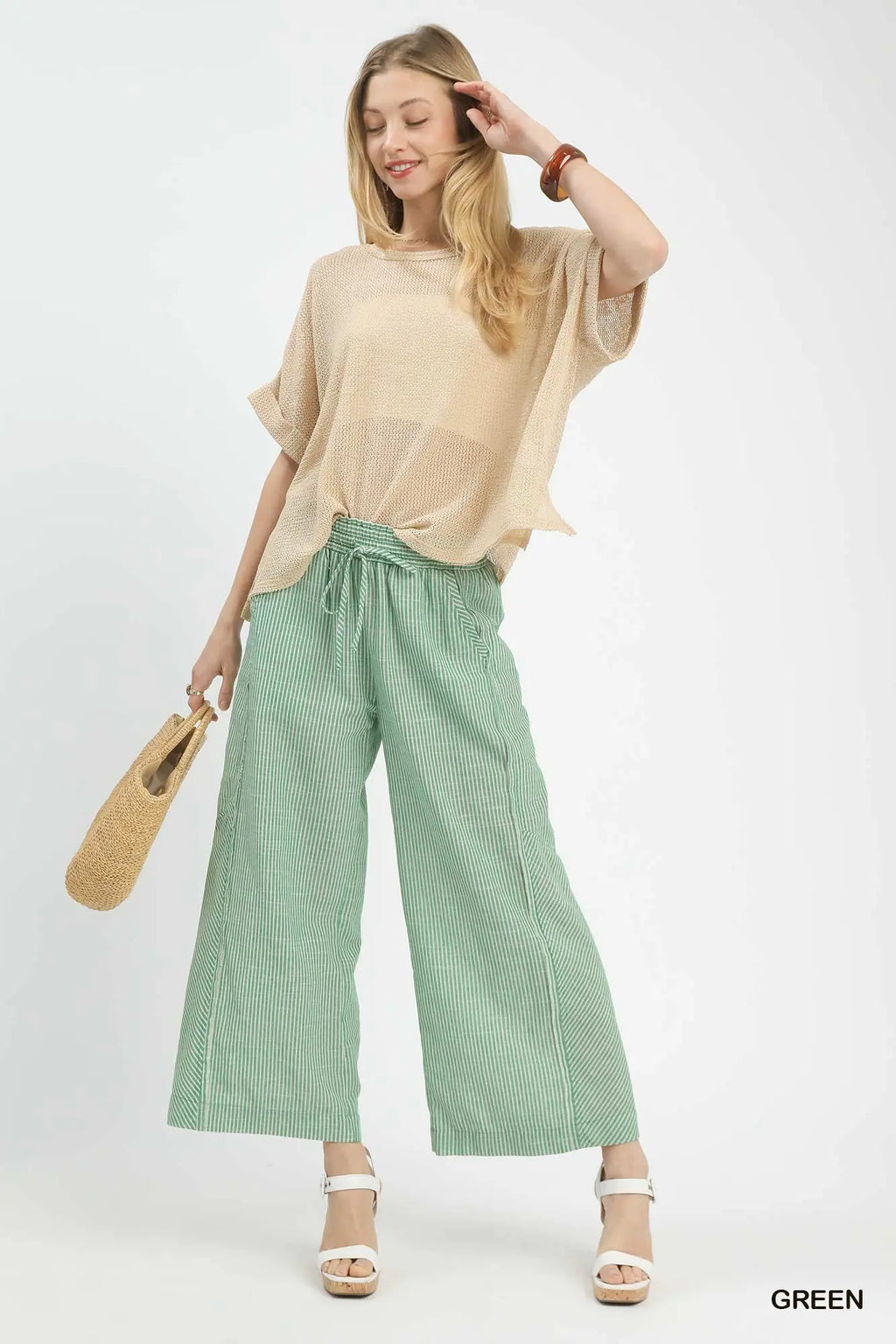 Woman wearing a beige top and green checkered pants on a white background