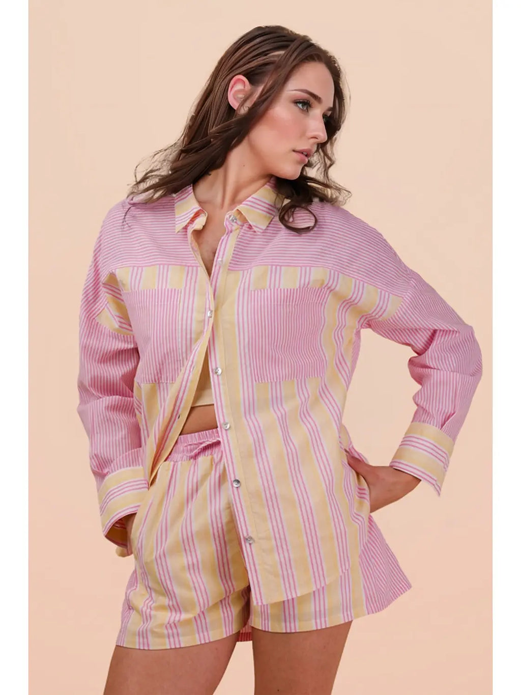 Woman wearing a pink and yellow striped shirt and shorts on a beige background