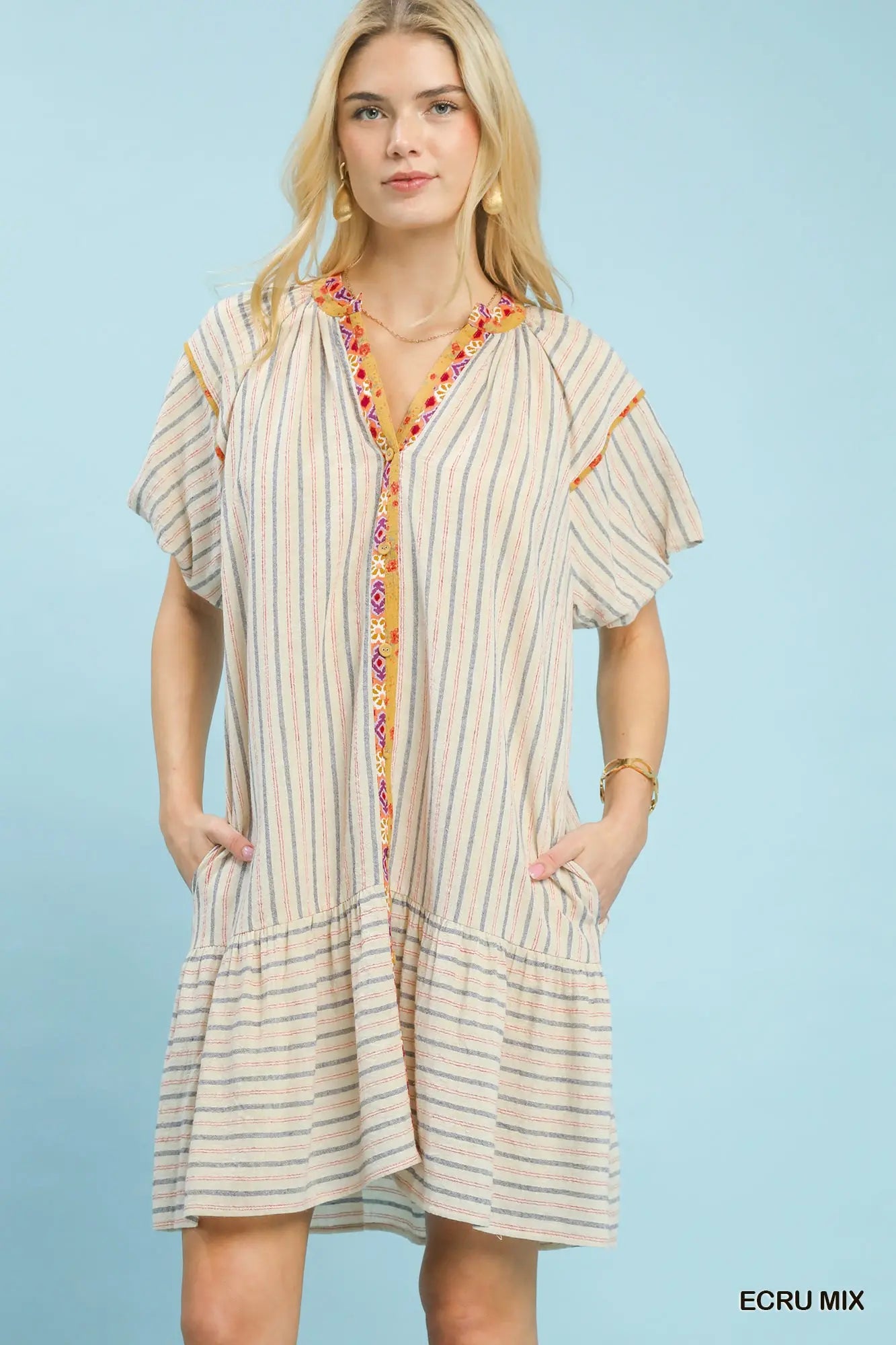 Woman wearing a striped dress with a colorful trim on a light blue background