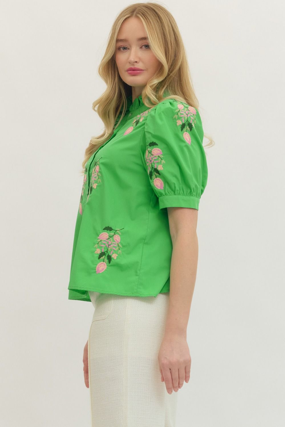 Woman wearing a green blouse with floral embroidery on a white background