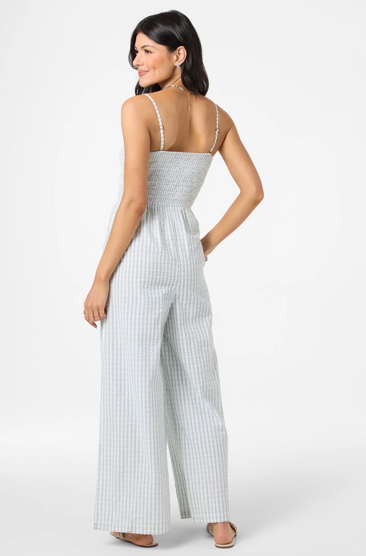 Woman wearing a light blue and white striped jumpsuit on a white background
