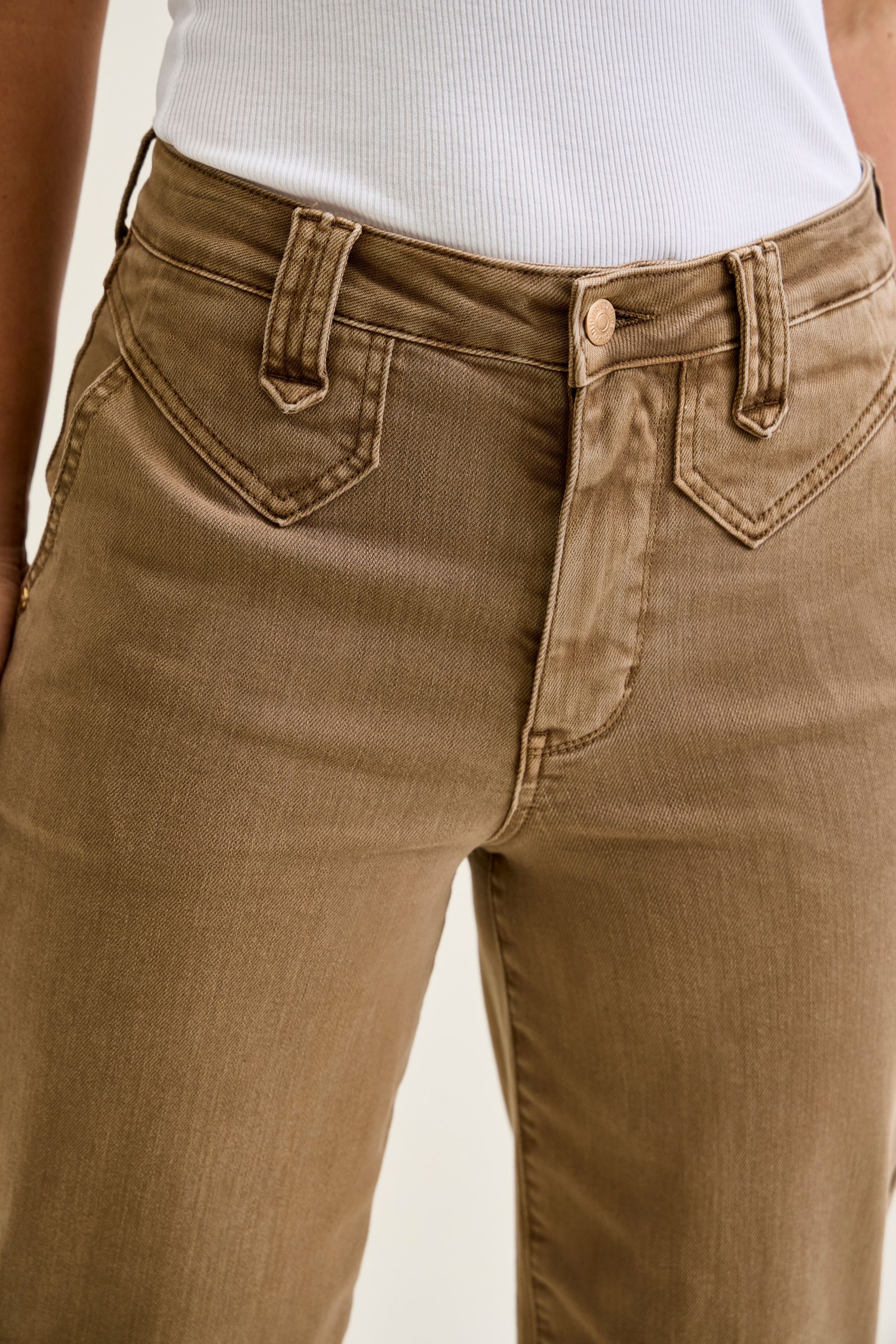 Brown jeans worn by a person on a plain background