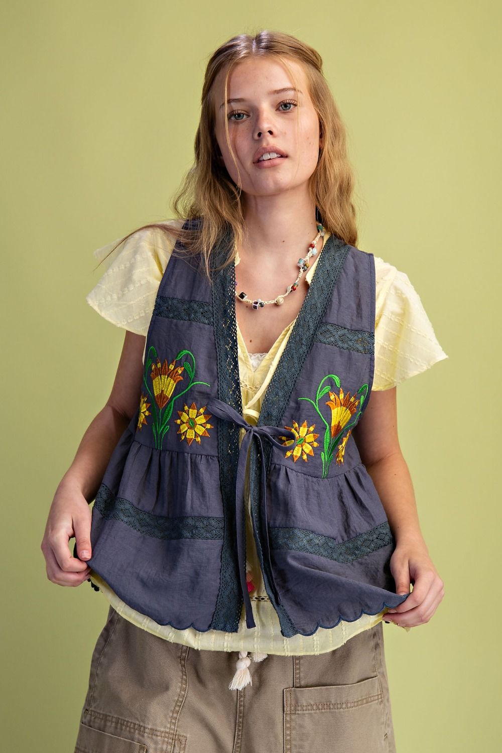 Woman wearing a colorful embroidered vest on a green background