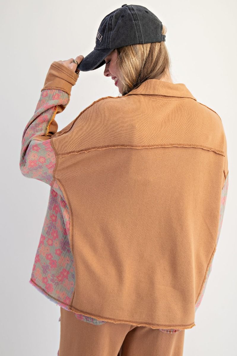 Person wearing a tan jacket with floral lining, black cap, and beige pants on a white background