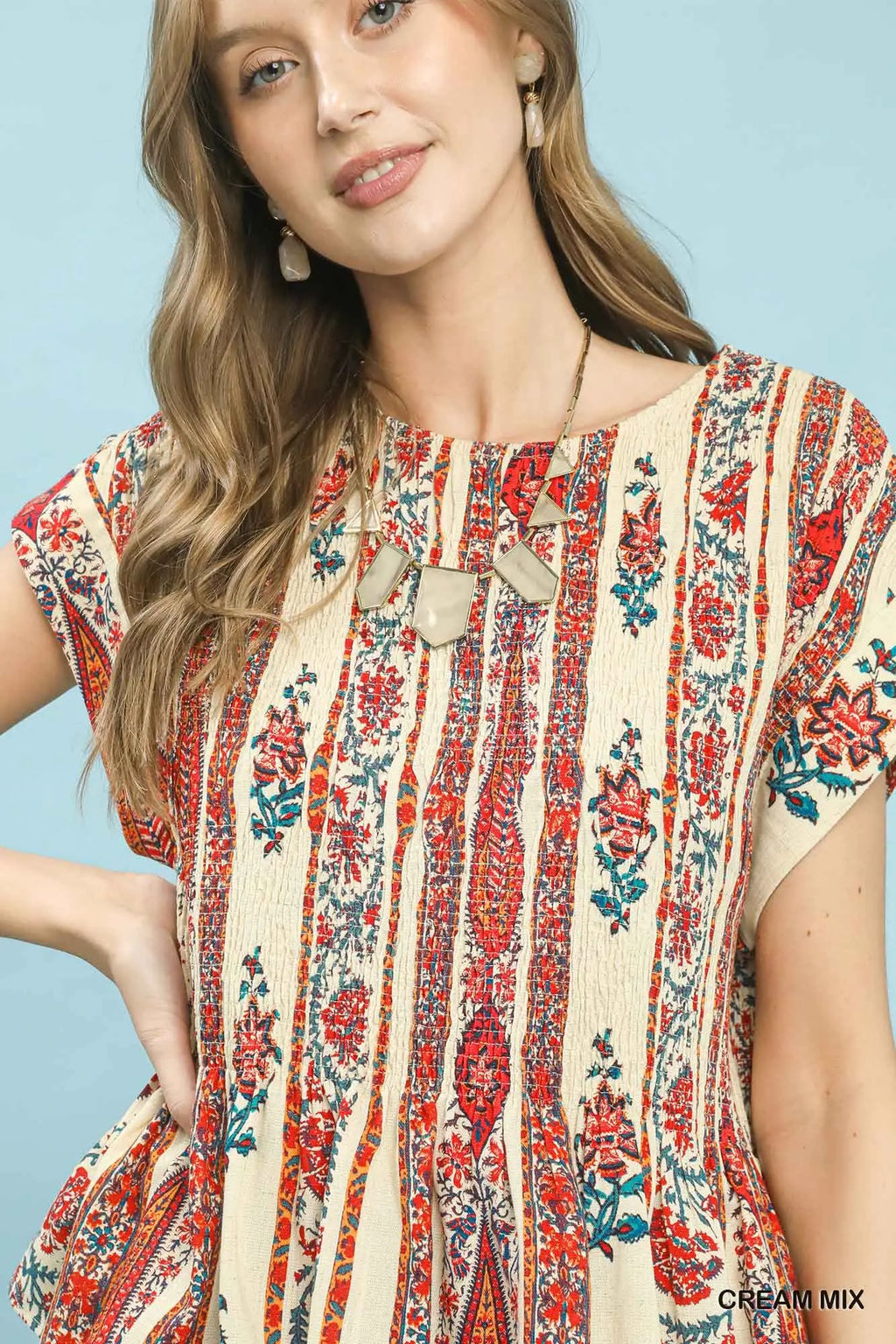 Woman wearing a colorful patterned dress against a light blue background