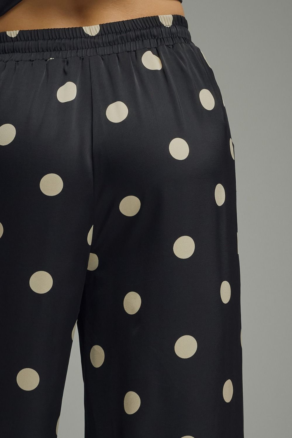 Black pants with beige polka dots on a gray background