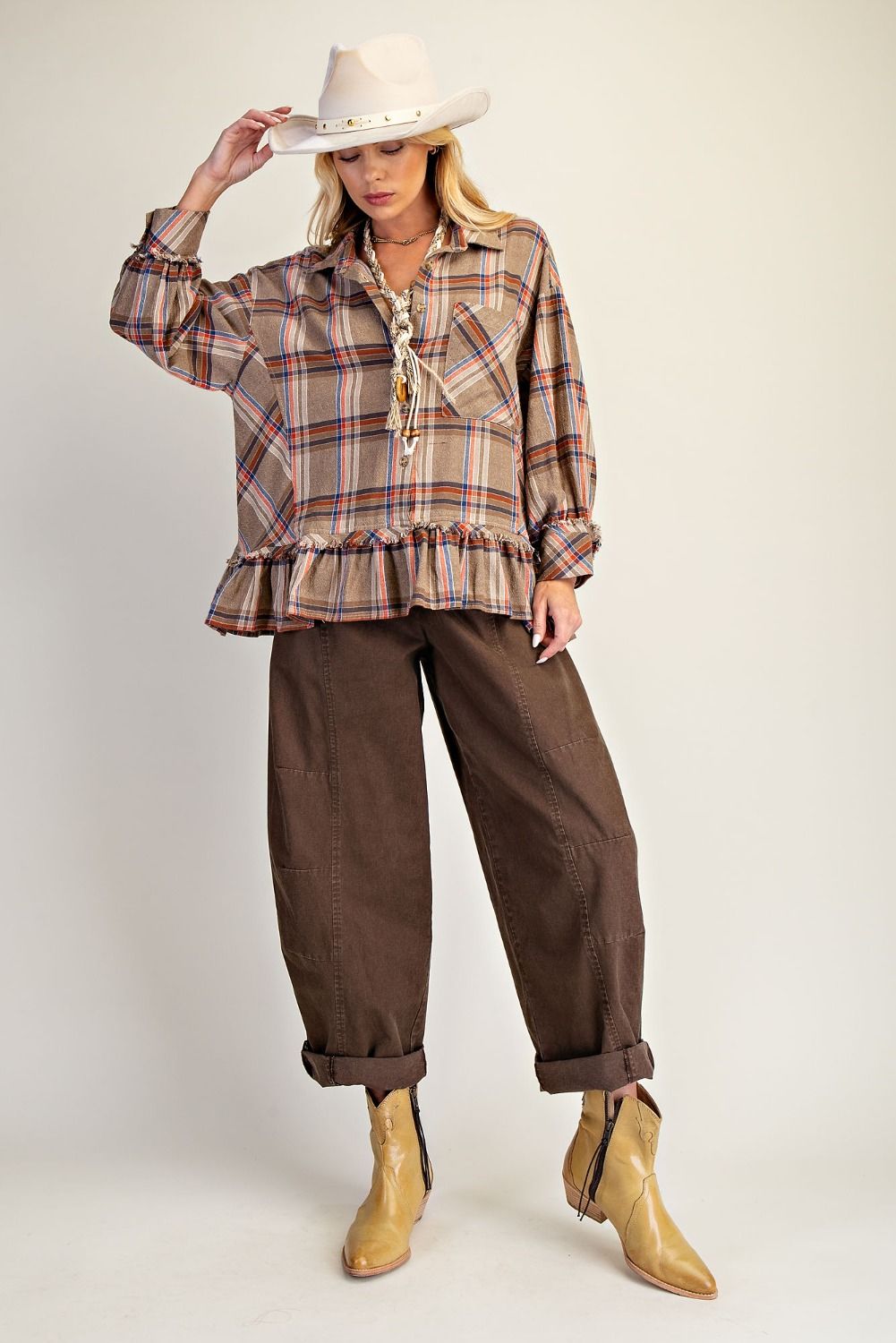 Woman wearing a plaid shirt, brown pants, and tan boots on a white background