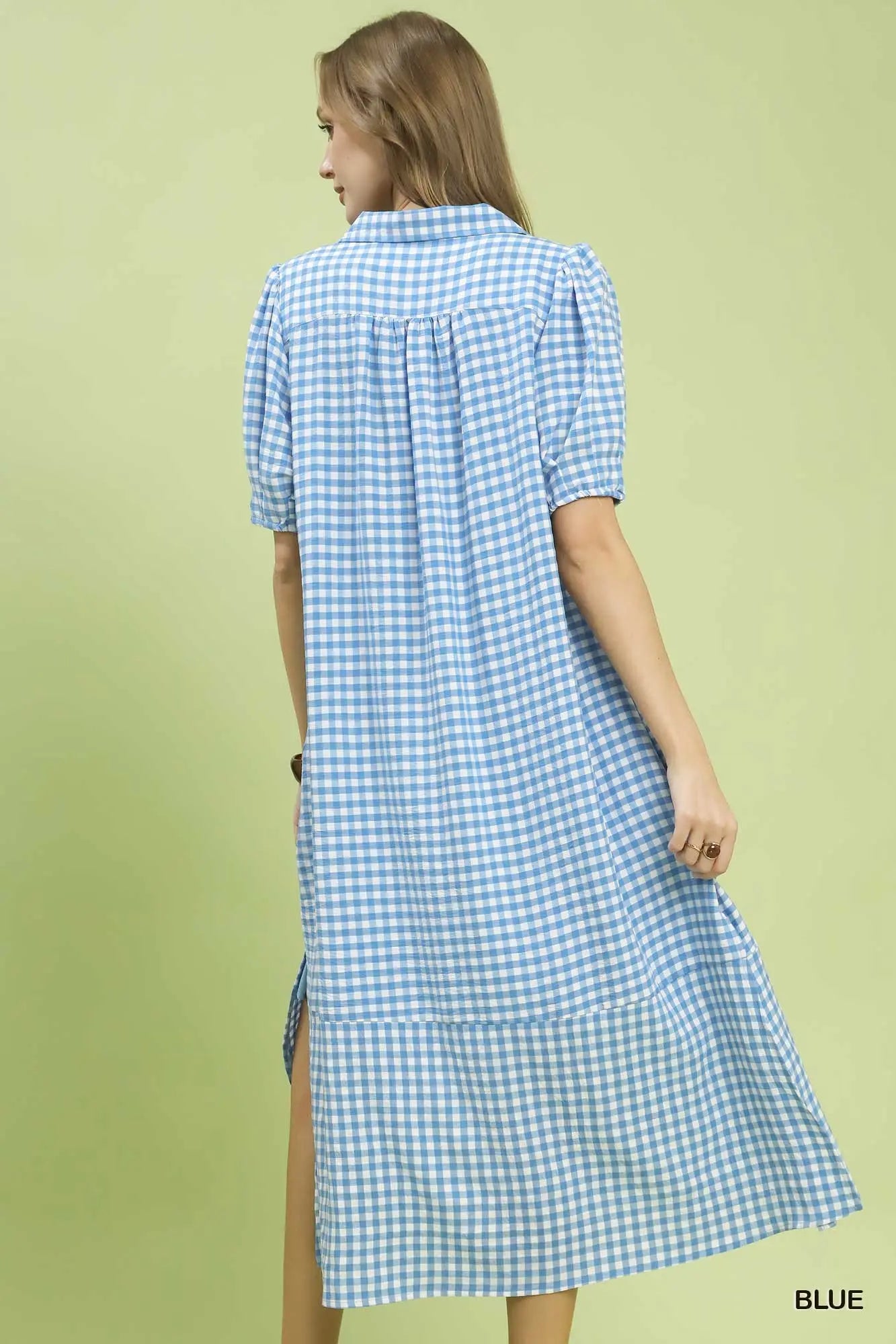 Woman wearing a blue and white checkered dress on a light green background