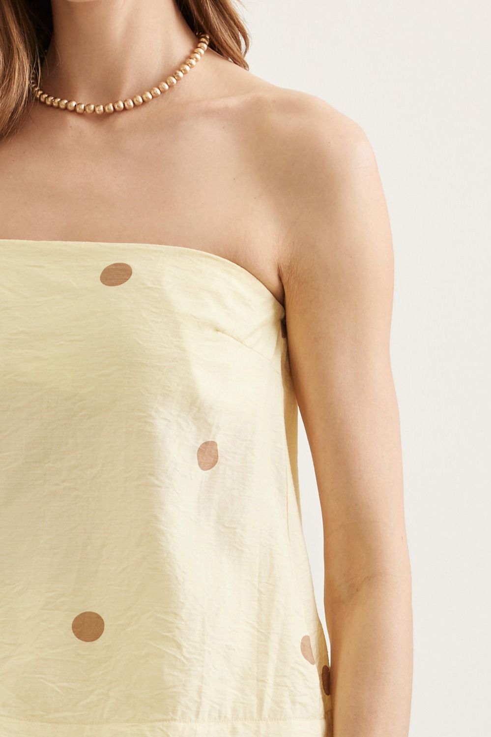 Light green strapless dress with brown buttons on a plain background