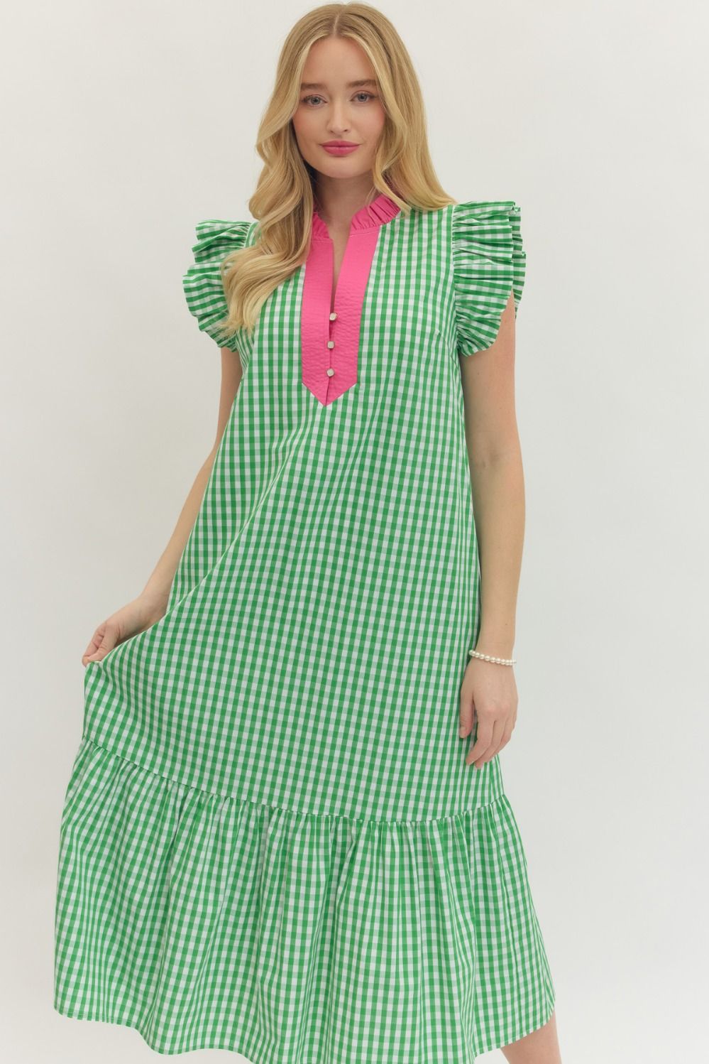 Woman wearing a green checkered dress with pink accents on a white background