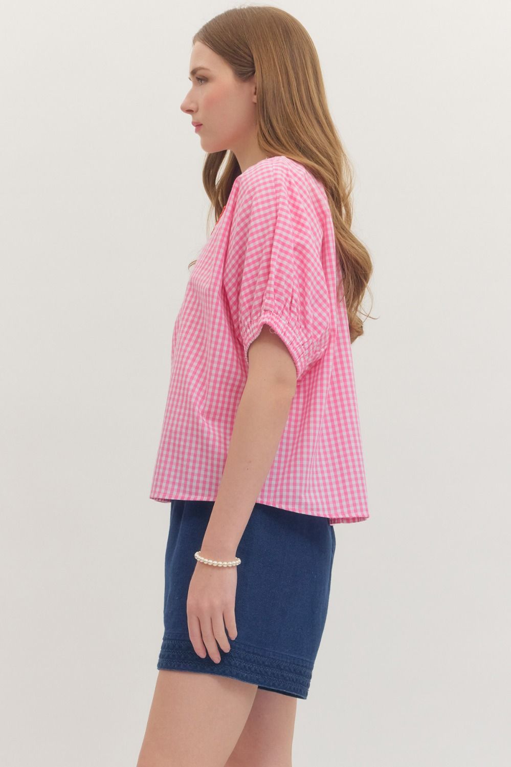 Woman wearing a pink checkered top and blue skirt on a plain background