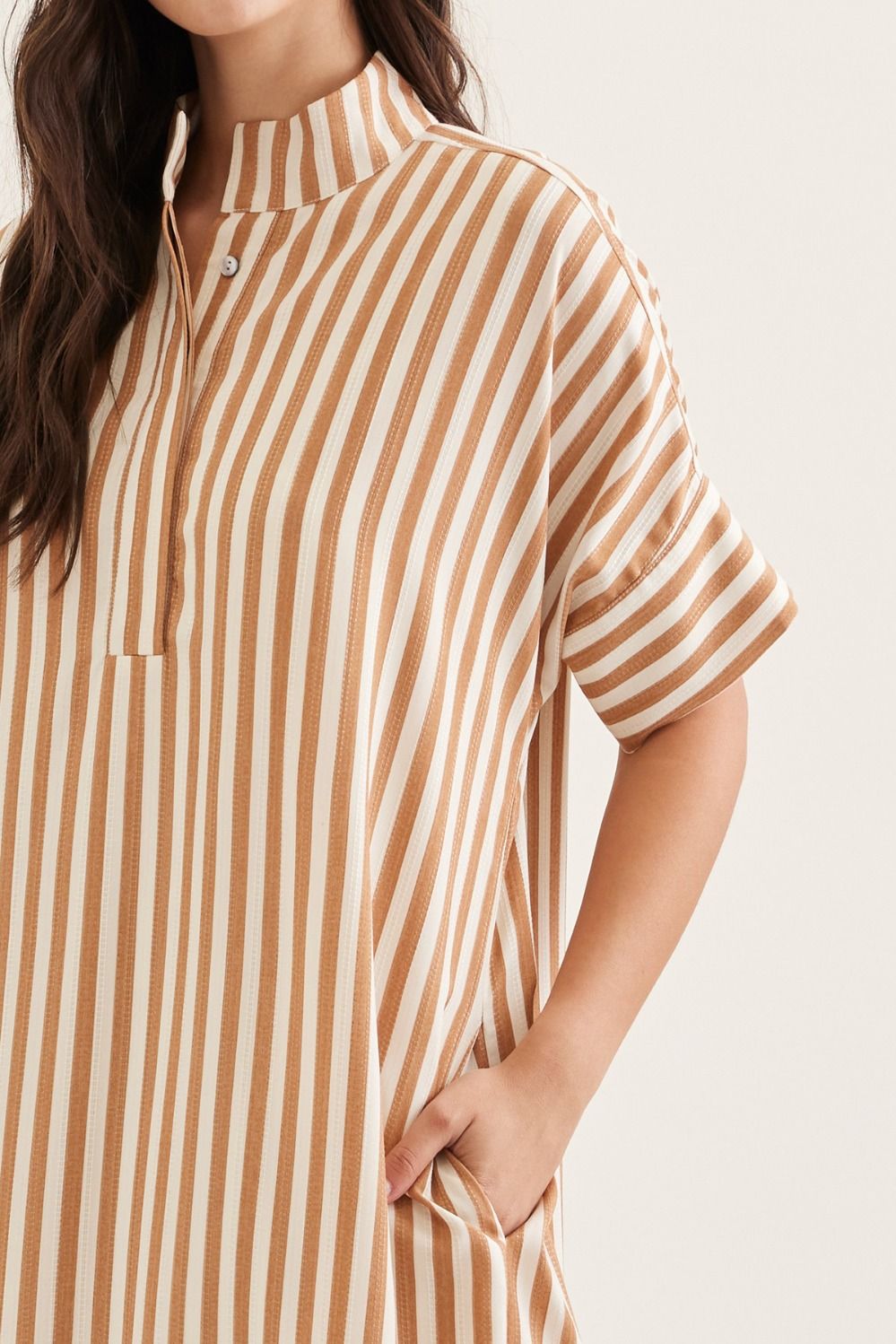 Person wearing a brown and white striped shirt on a plain background