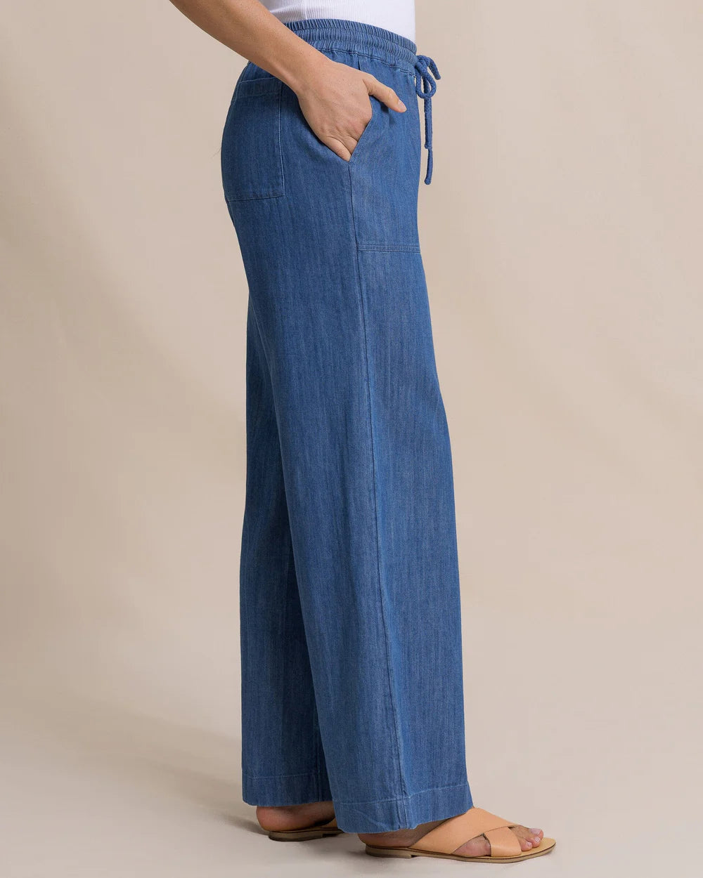 Blue denim pants worn by a person on a beige background