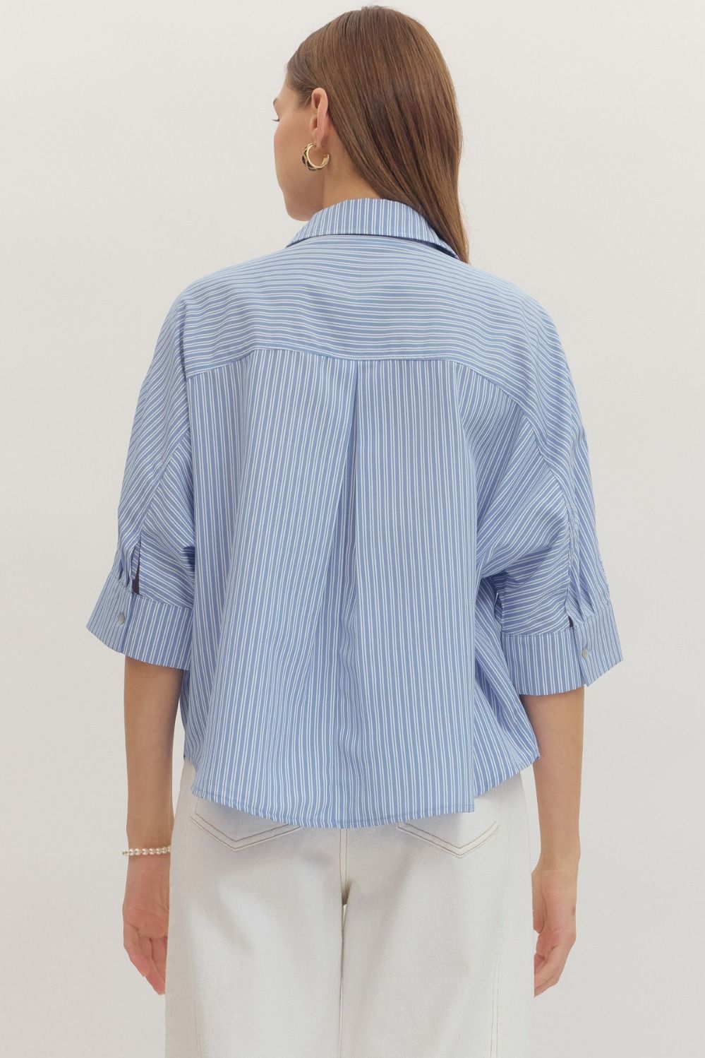Person wearing a blue striped shirt on a plain background