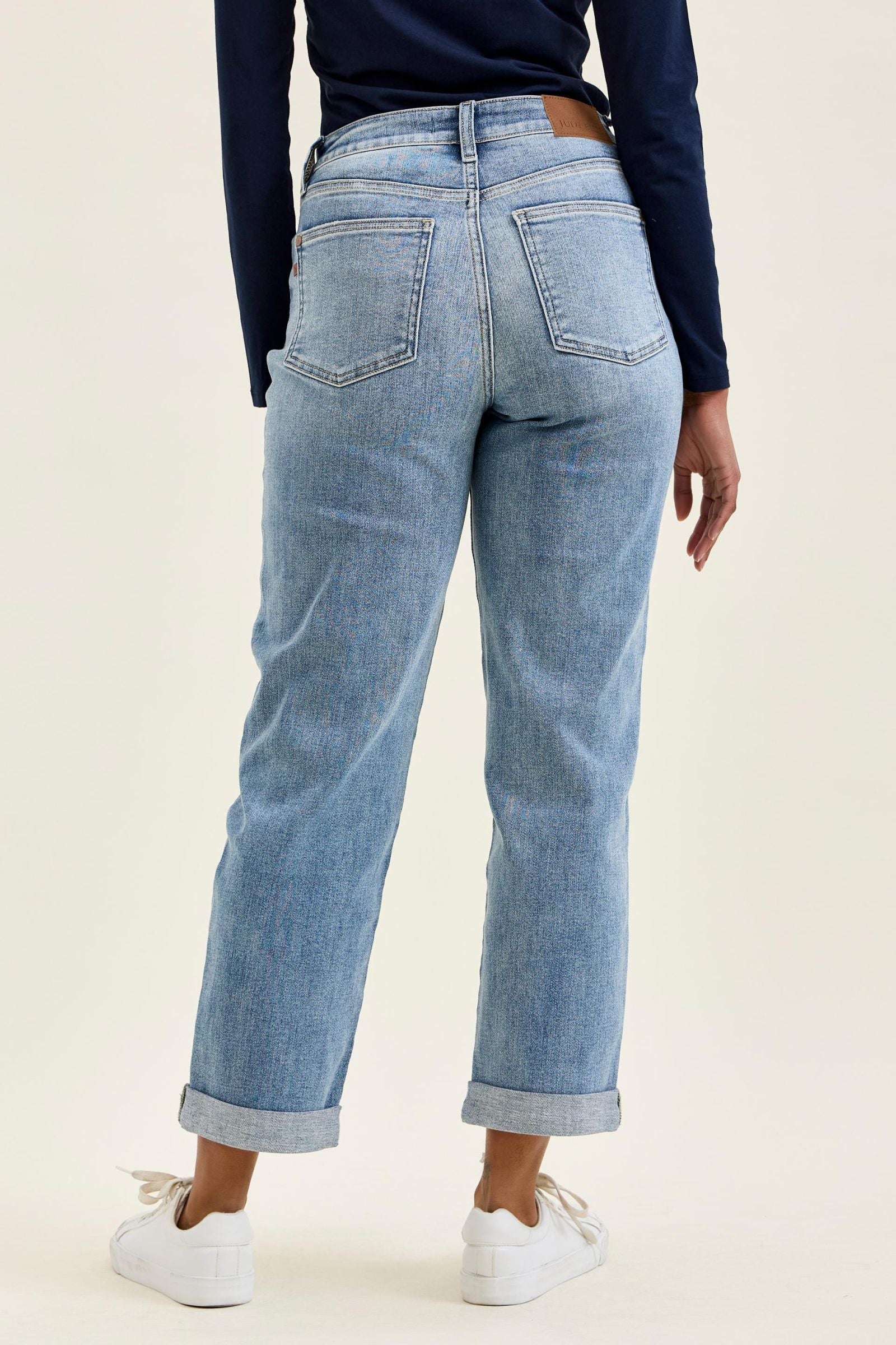 Person wearing light blue jeans with a plain background
