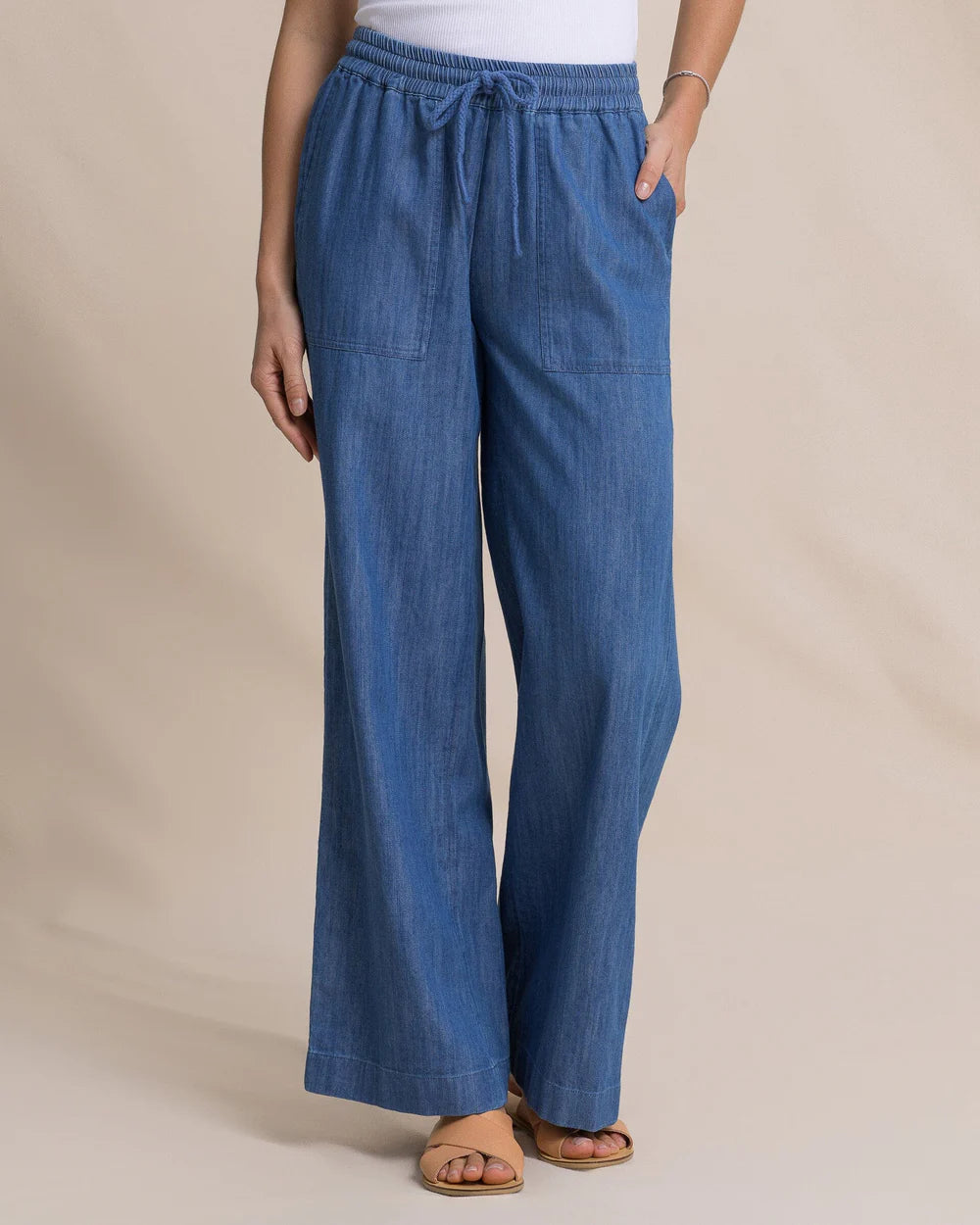 Blue wide-leg pants worn by a person on a beige background