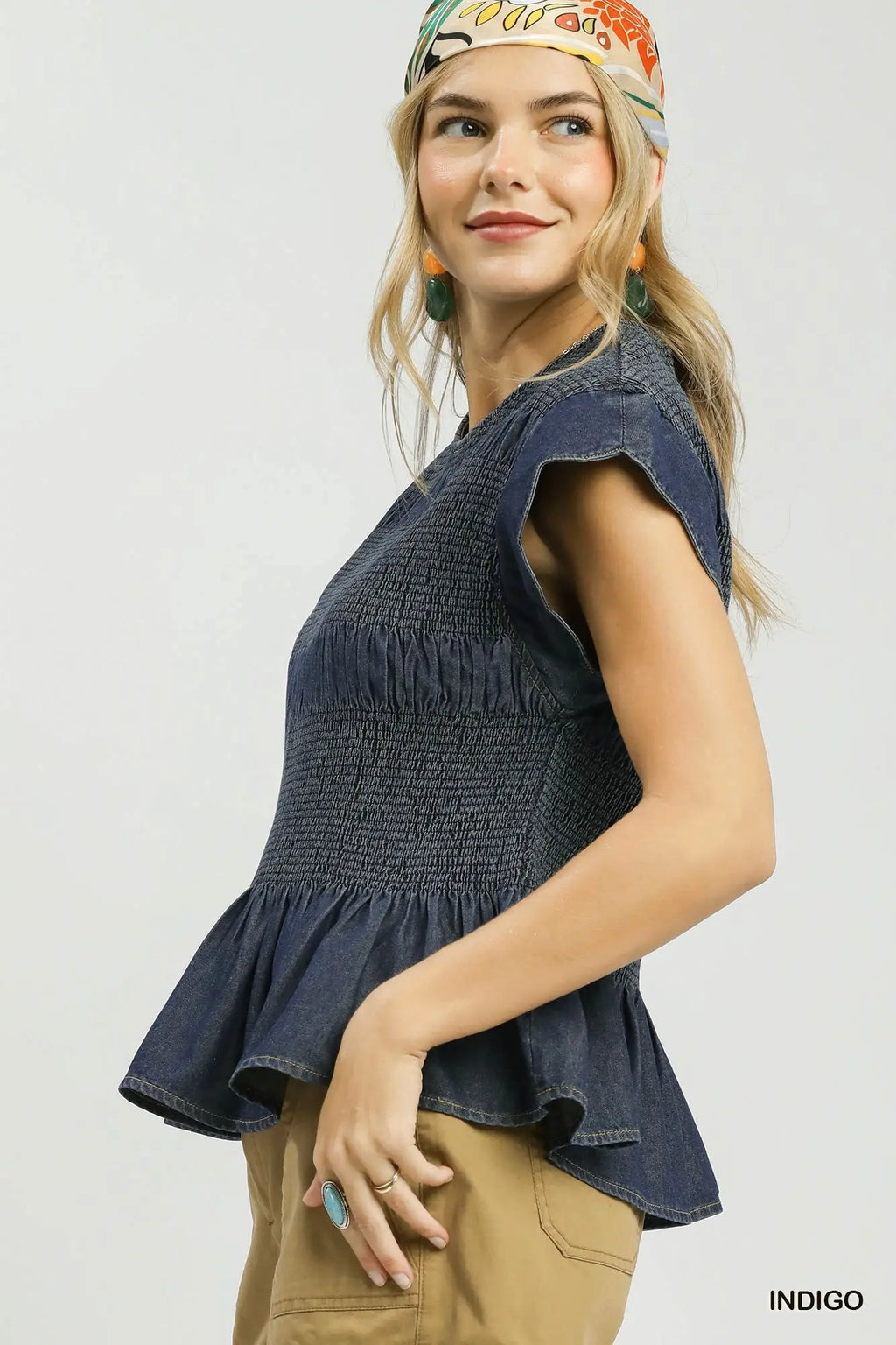 Woman wearing a blue sleeveless top with a white background