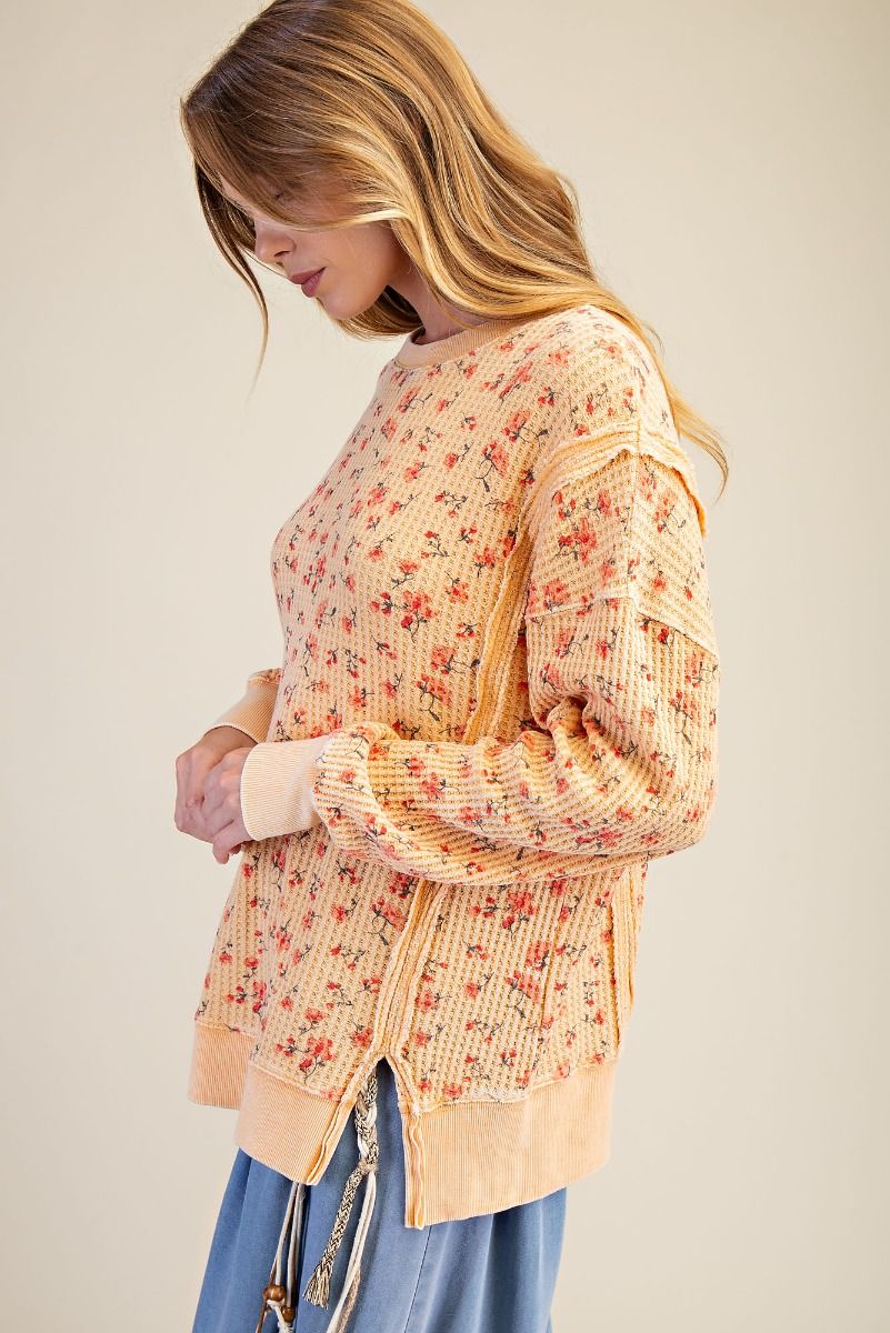 Woman wearing a floral cardigan over a beige top with a neutral background