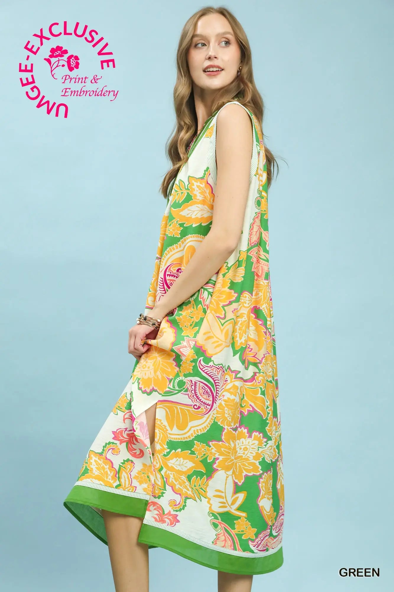 Woman wearing a colorful floral dress on a light blue background with Umgee branding.