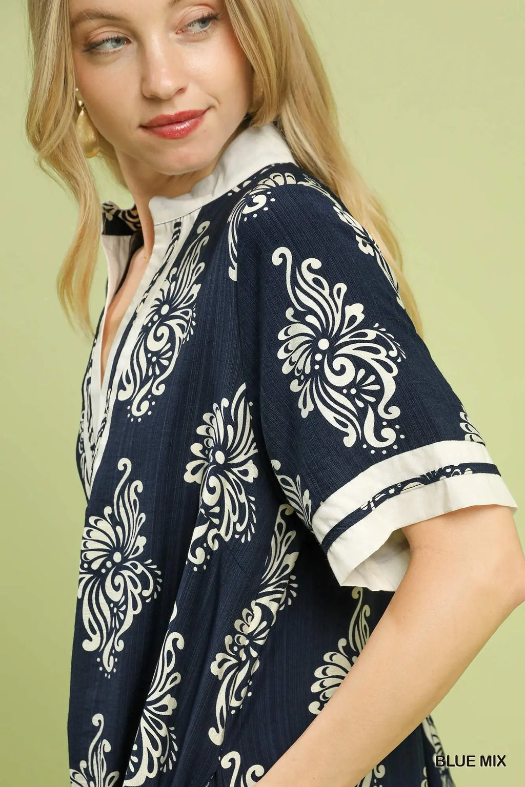 Woman wearing a navy blue kimono with white floral patterns on a light green background