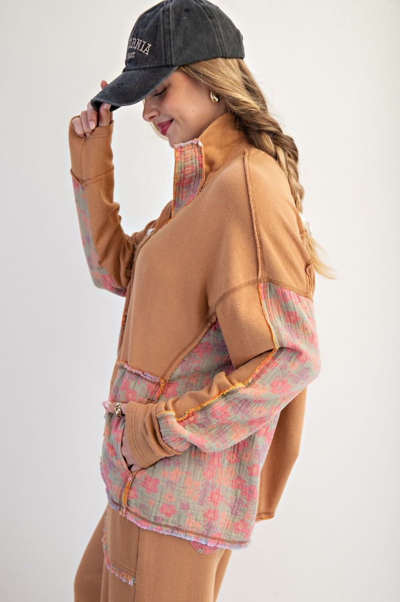 Woman wearing a brown and plaid jacket with a black cap on a white background