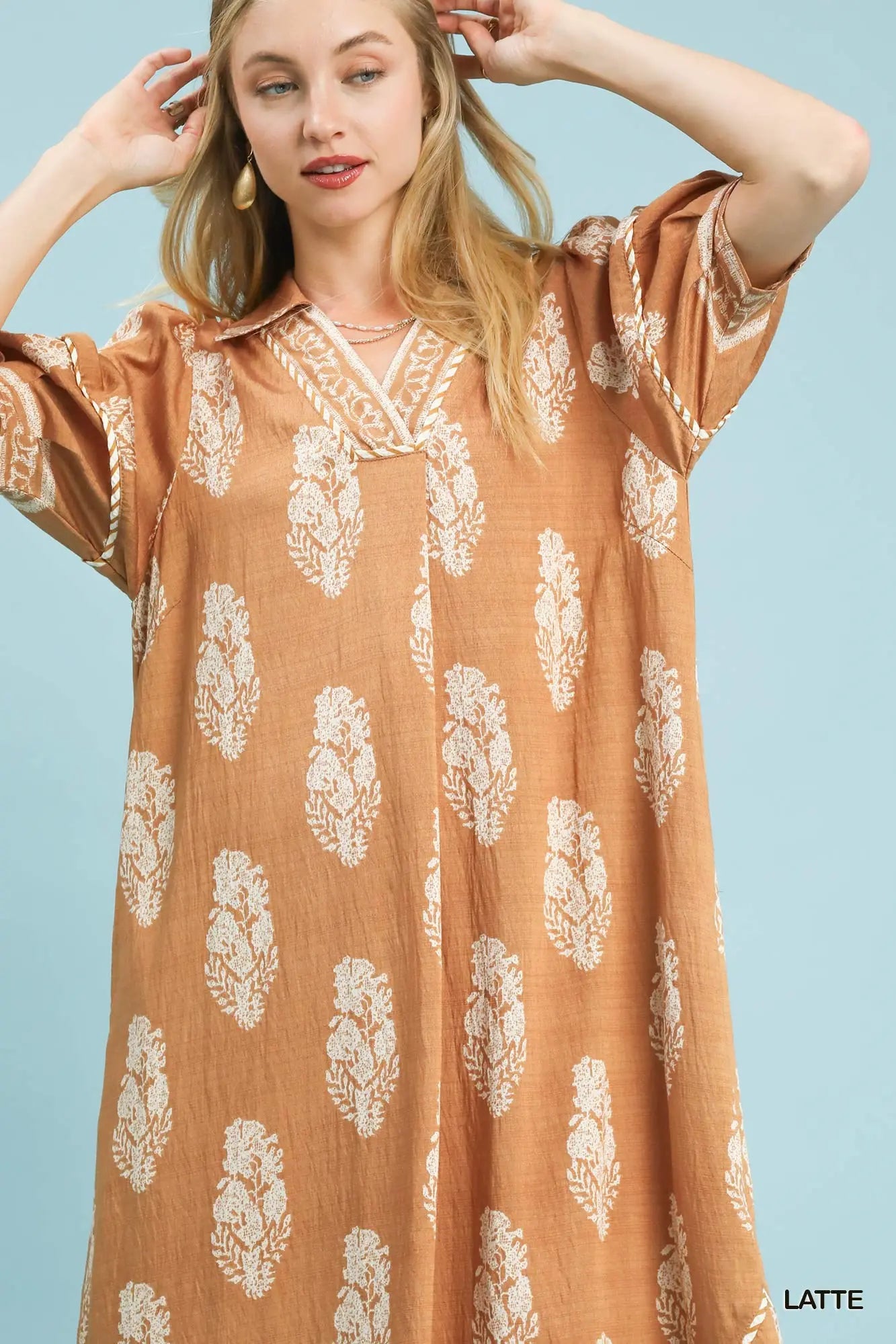 Woman wearing a brown dress with white floral patterns against a light blue background
