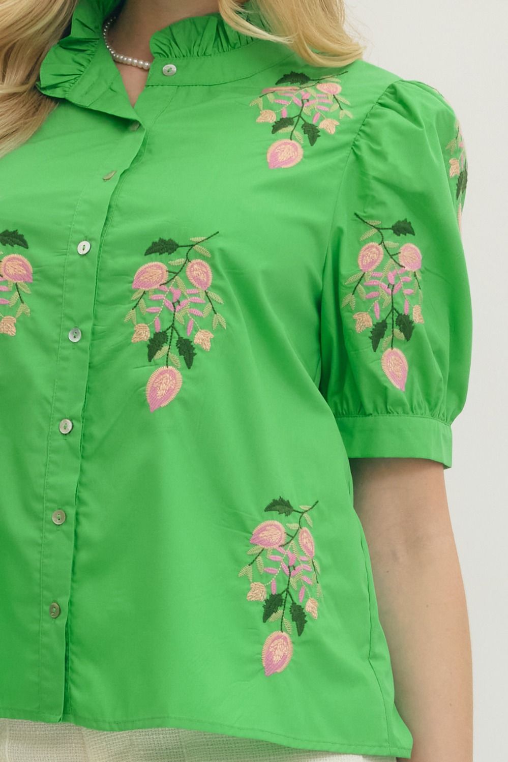 Green blouse with floral embroidery on a plain background