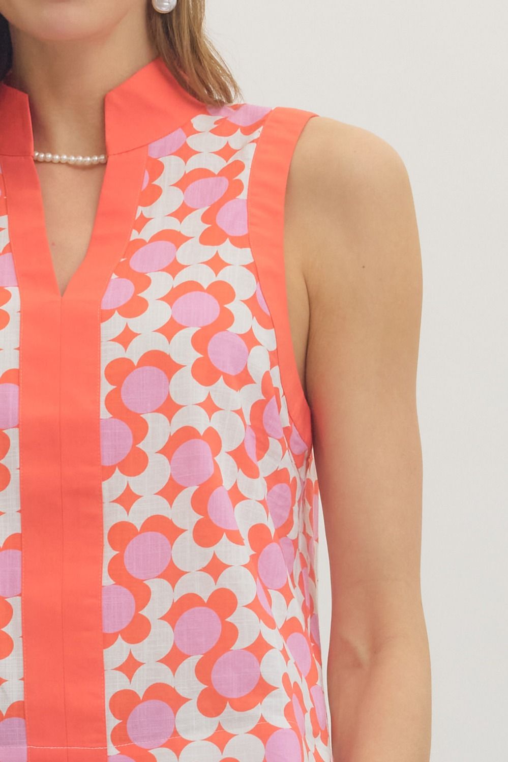 Woman wearing a sleeveless dress with a floral pattern on a plain background