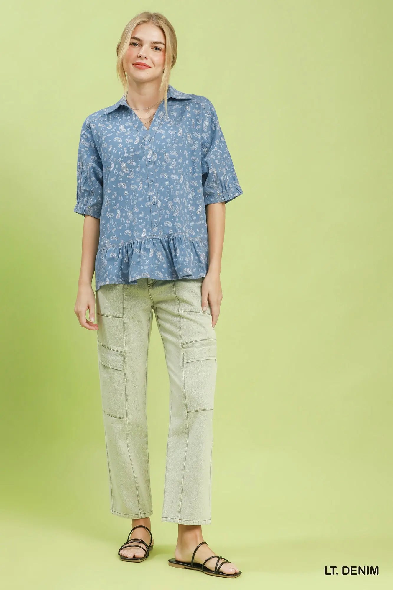 Woman wearing a blue floral blouse and beige pants on a green background