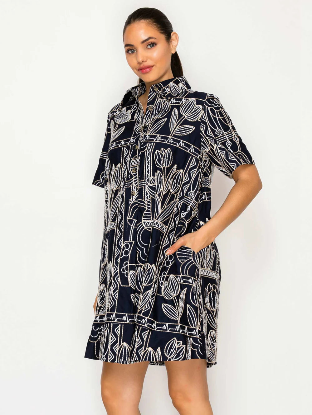 Woman wearing a navy dress with white floral pattern on a white background