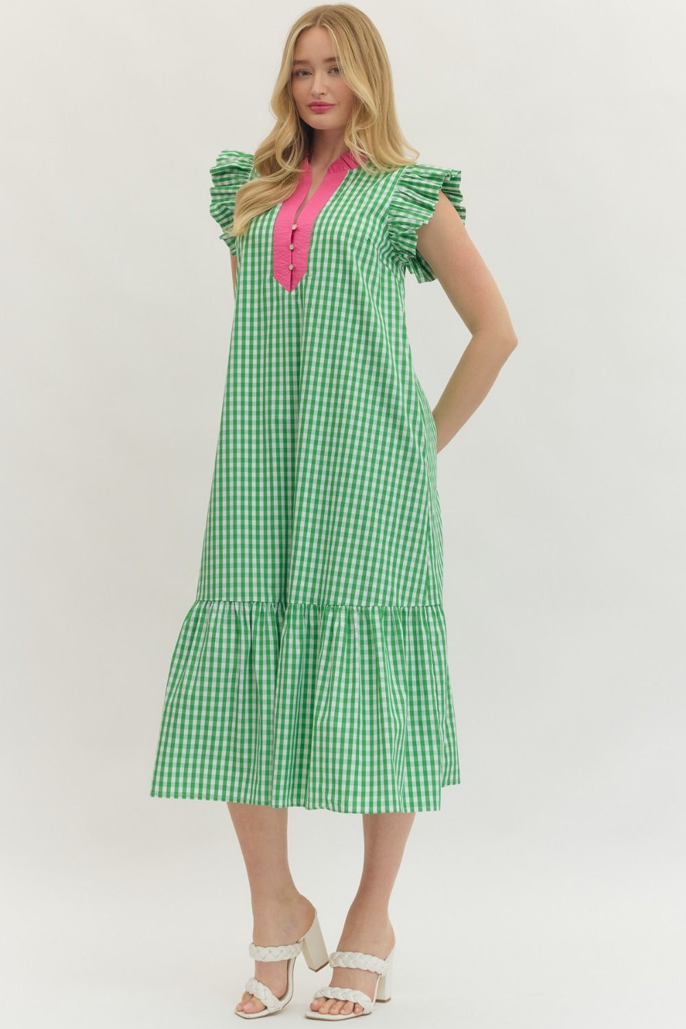 Woman wearing a green checkered dress with a pink top on a white background