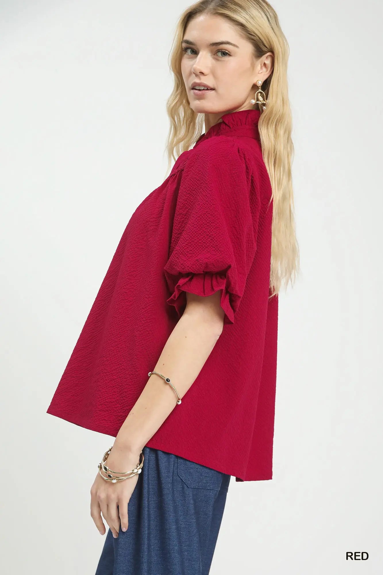 Woman wearing a red blouse with ruffled sleeves on a white background