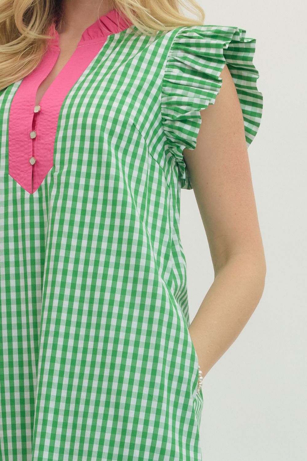 Green and white checkered dress with pink neckline on a plain background