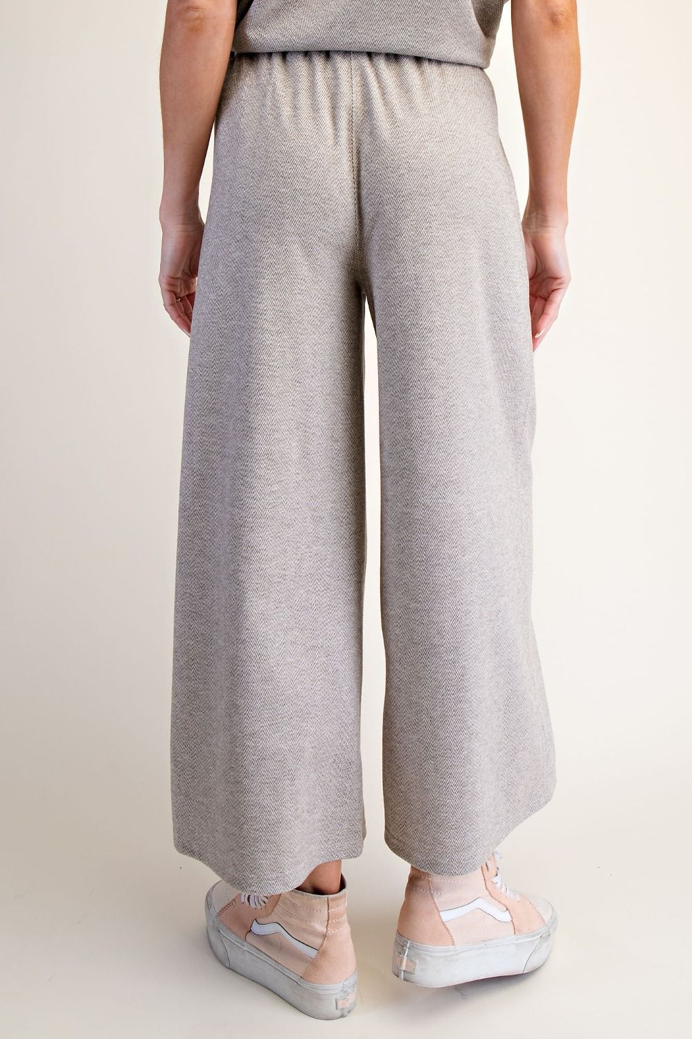 Person wearing light gray wide-leg pants on a beige background