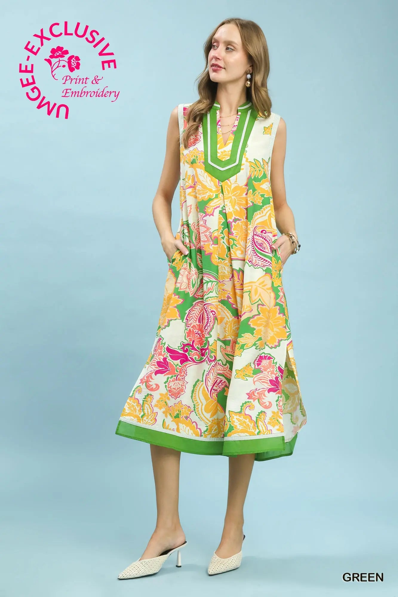 Woman wearing a colorful floral dress on a light blue background with Umgee branding.