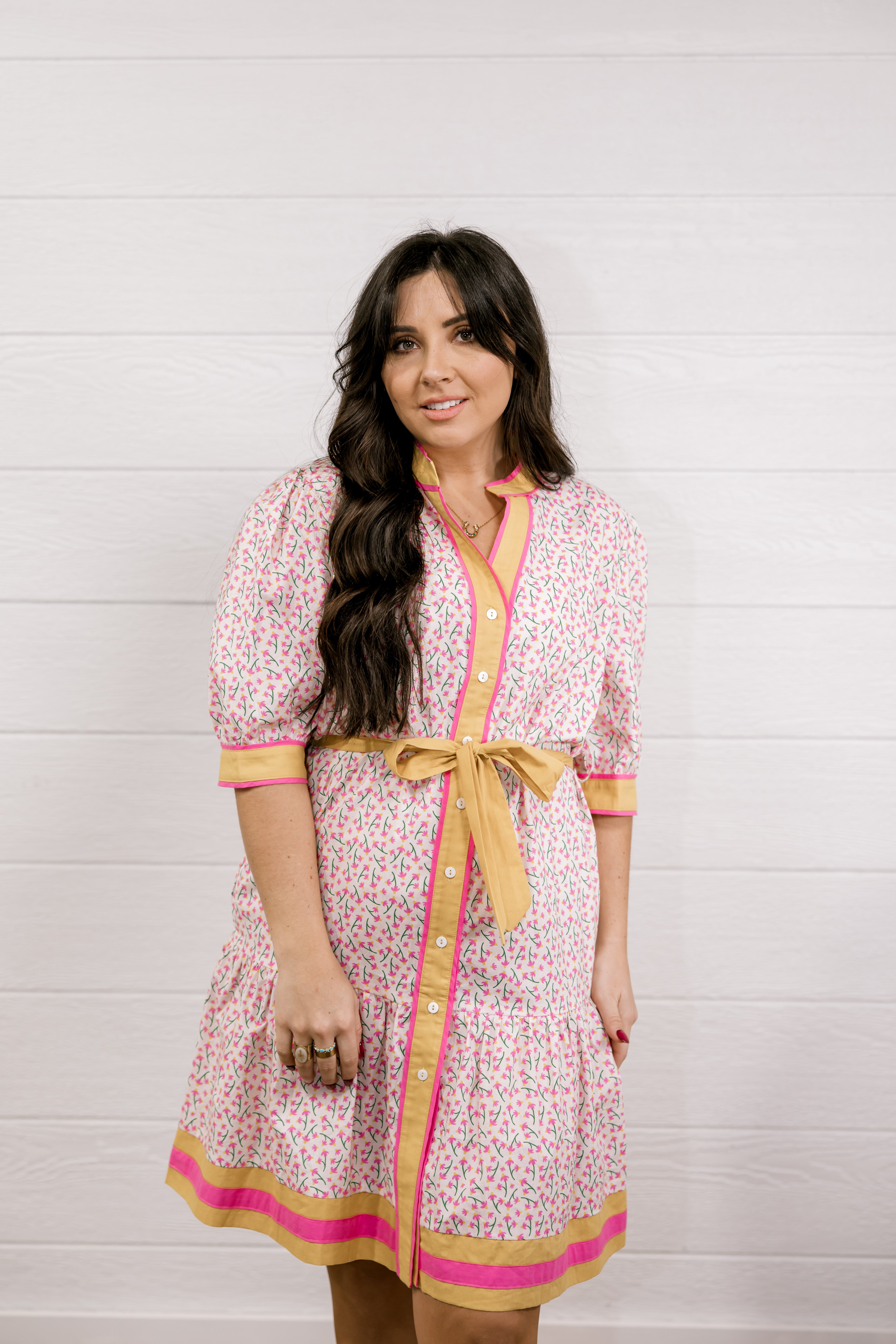 Woman wearing a patterned dress with a bow tie against a white background