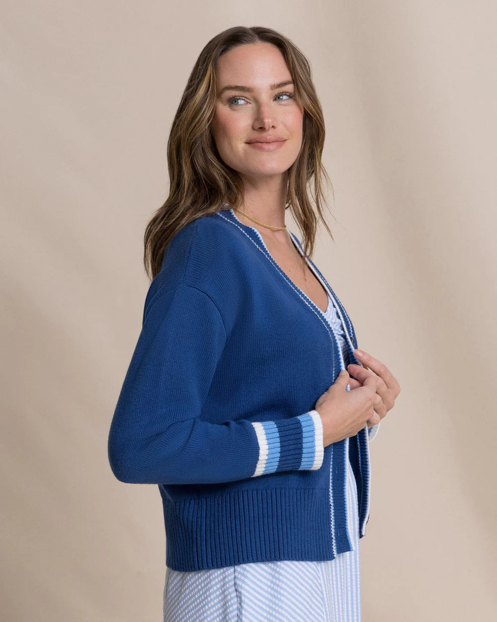 Woman wearing a blue cardigan against a beige background
