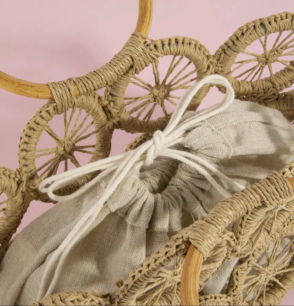 Woven basket with a drawstring bag inside against a pink background